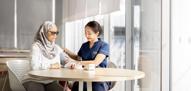 NUHS healthcare staff taking blood pressure of a senior resident during a community health programme